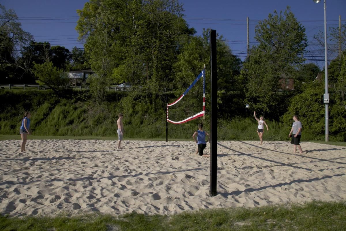 Beach volleyball court with players on sand and a net under a clear blue sky