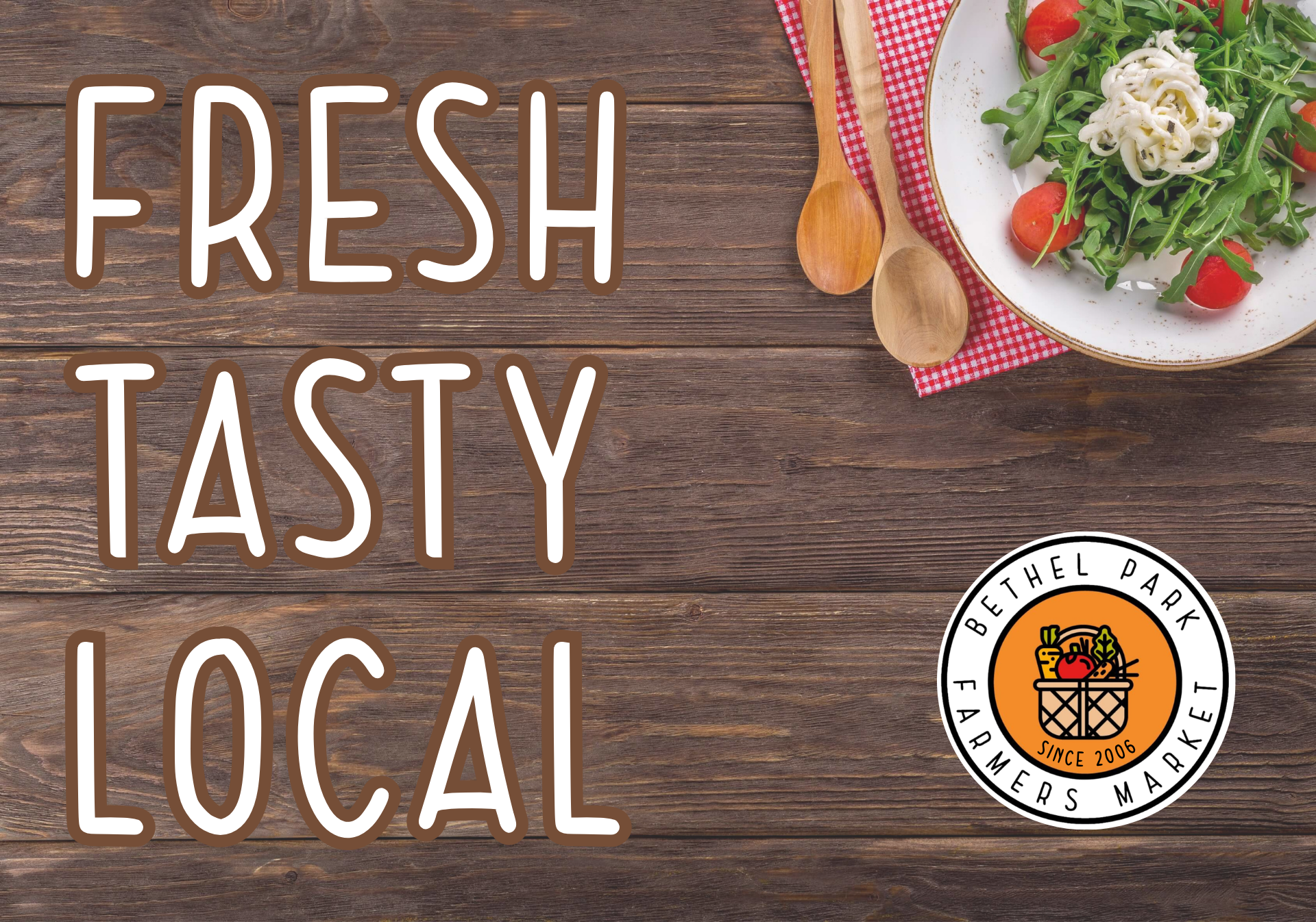 Fresh tasty local text on wood table with salad, spoon, fork, and farm-fresh logo