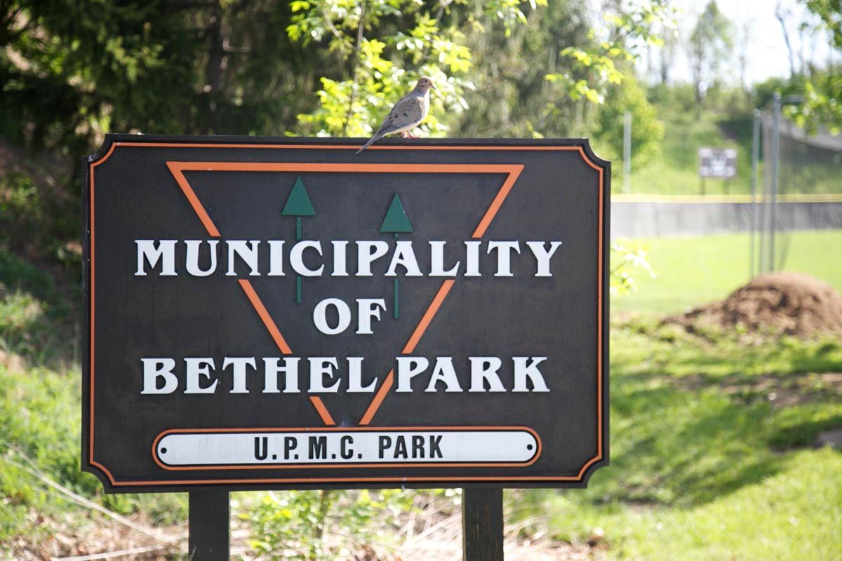Sign for Municipality of Bethel Park, U.P.M.C. Park, on a black post in a grassy area