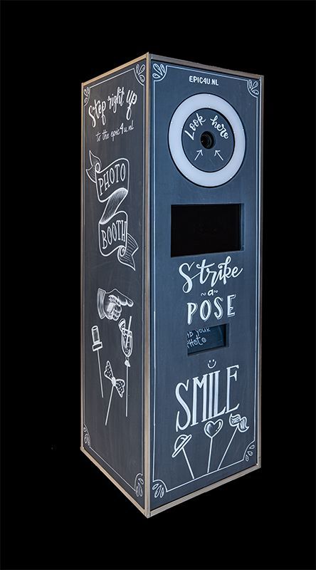 Grijze fotobooth met een ronde cameralens en de tekst ‘Strike a Pose’ en ‘Smile’ op de voorkant.