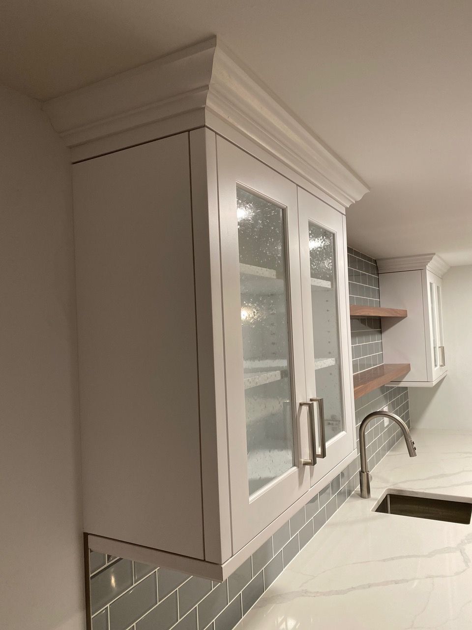 Cozy studio apartment with bed, sofa, kitchenette, and rug on wood-look floor.