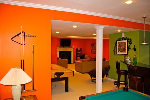 A brightly colored, open-concept basement with a pool table, bar, and seating areas.