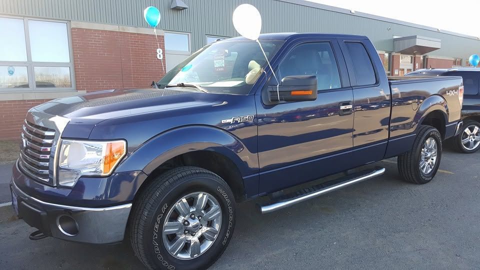 Dark blue pickup truck parked outside a dealership with balloons on the roofline | Randy Keach Auto Repair