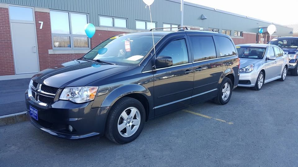Black minivan parked in a lot beside a silver car near a brick building, with a blue balloon visible nearby | Randy Keach Auto Repair