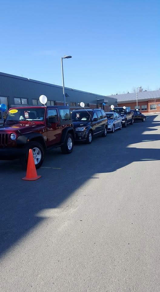 Line of parked cars beside a building, with a red SUV and orange cone in the foreground | Randy Keach Auto Repair