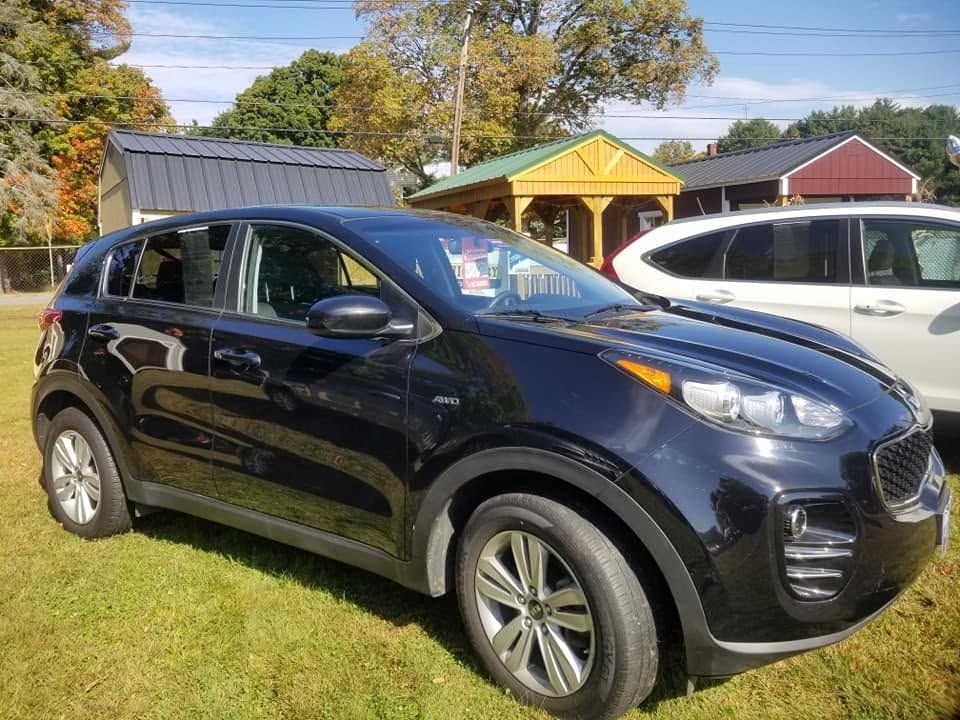 Black SUV parked on grass in a sunny yard with a yellow house and white minivan nearby | Randy Keach Auto Repair