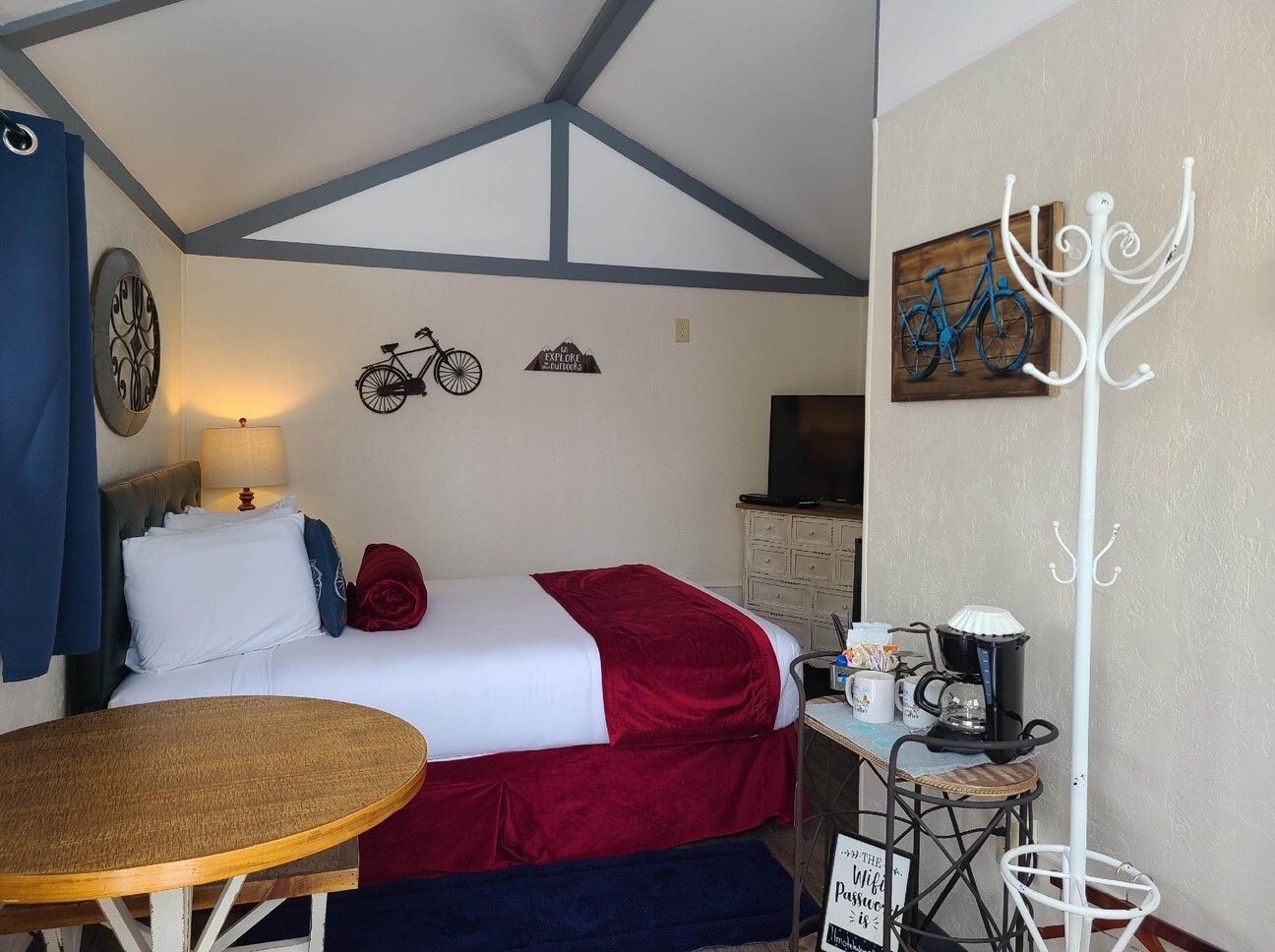 A bedroom with a king size bed , a table , and a coat rack.