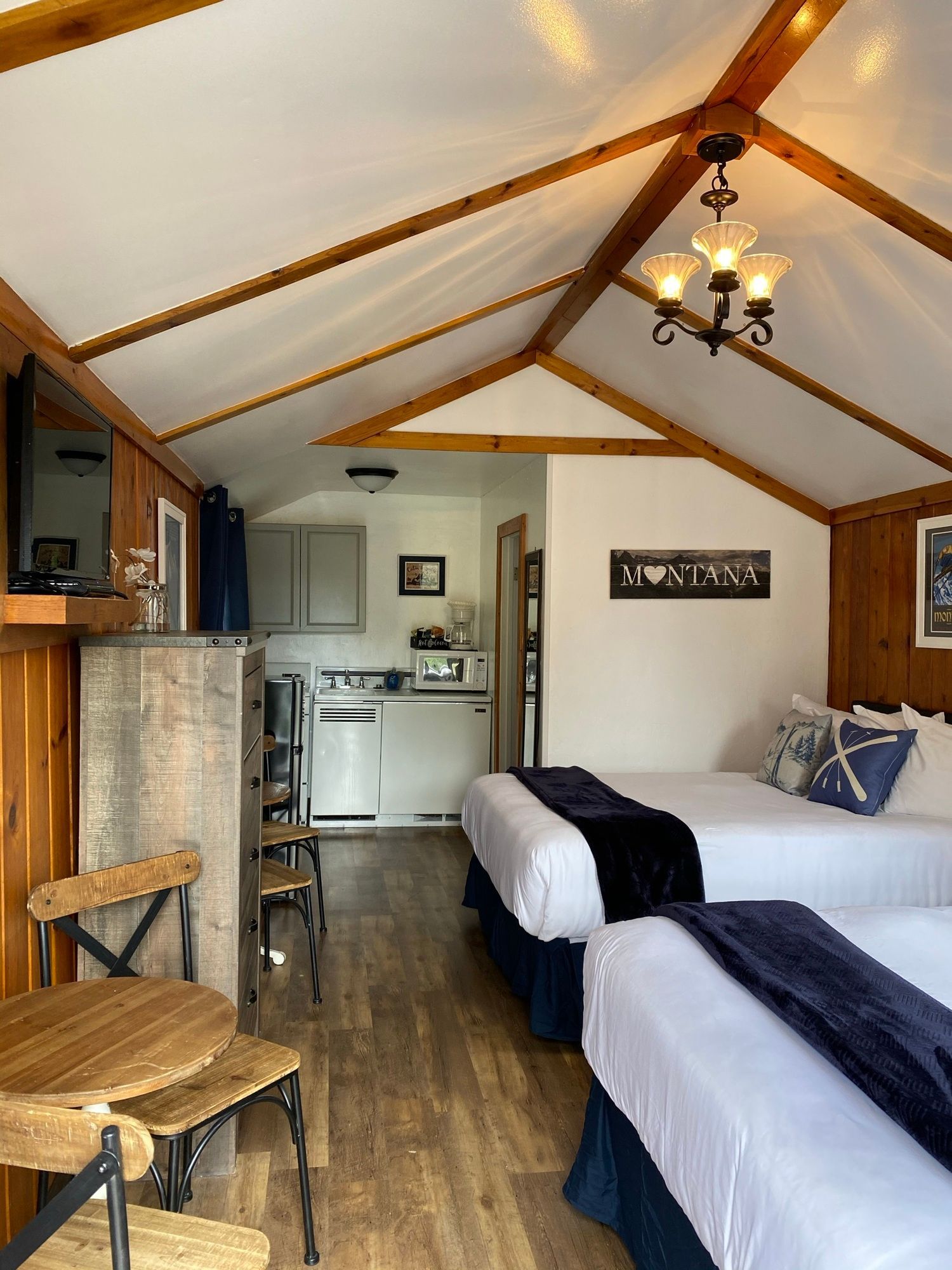 A room with two beds , a table , chairs and a television.