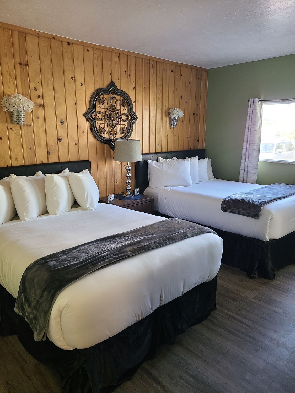 A hotel room with two beds and a clock on the wall.