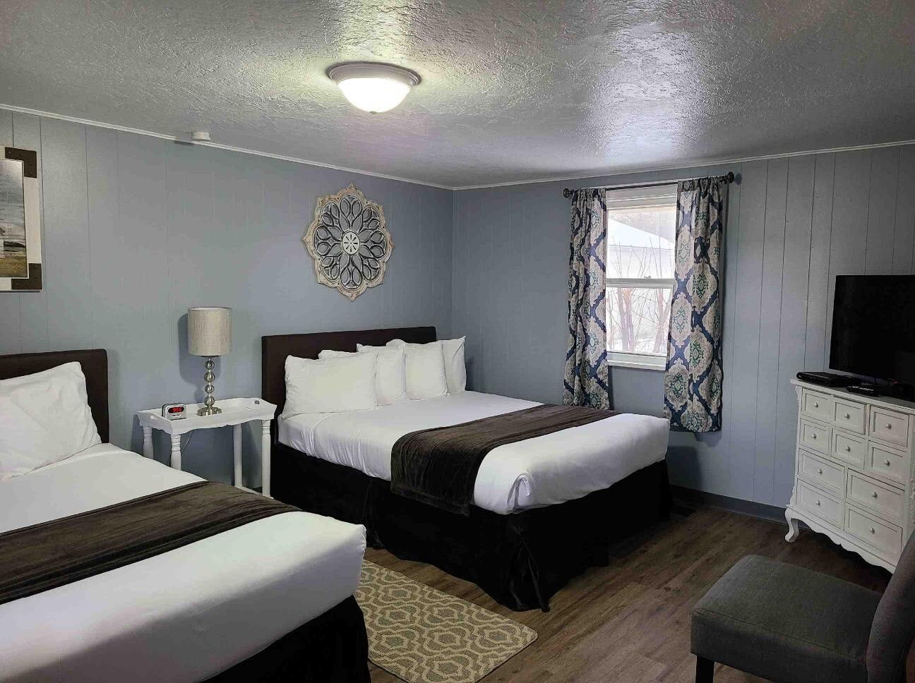 A hotel room with two beds and a television.