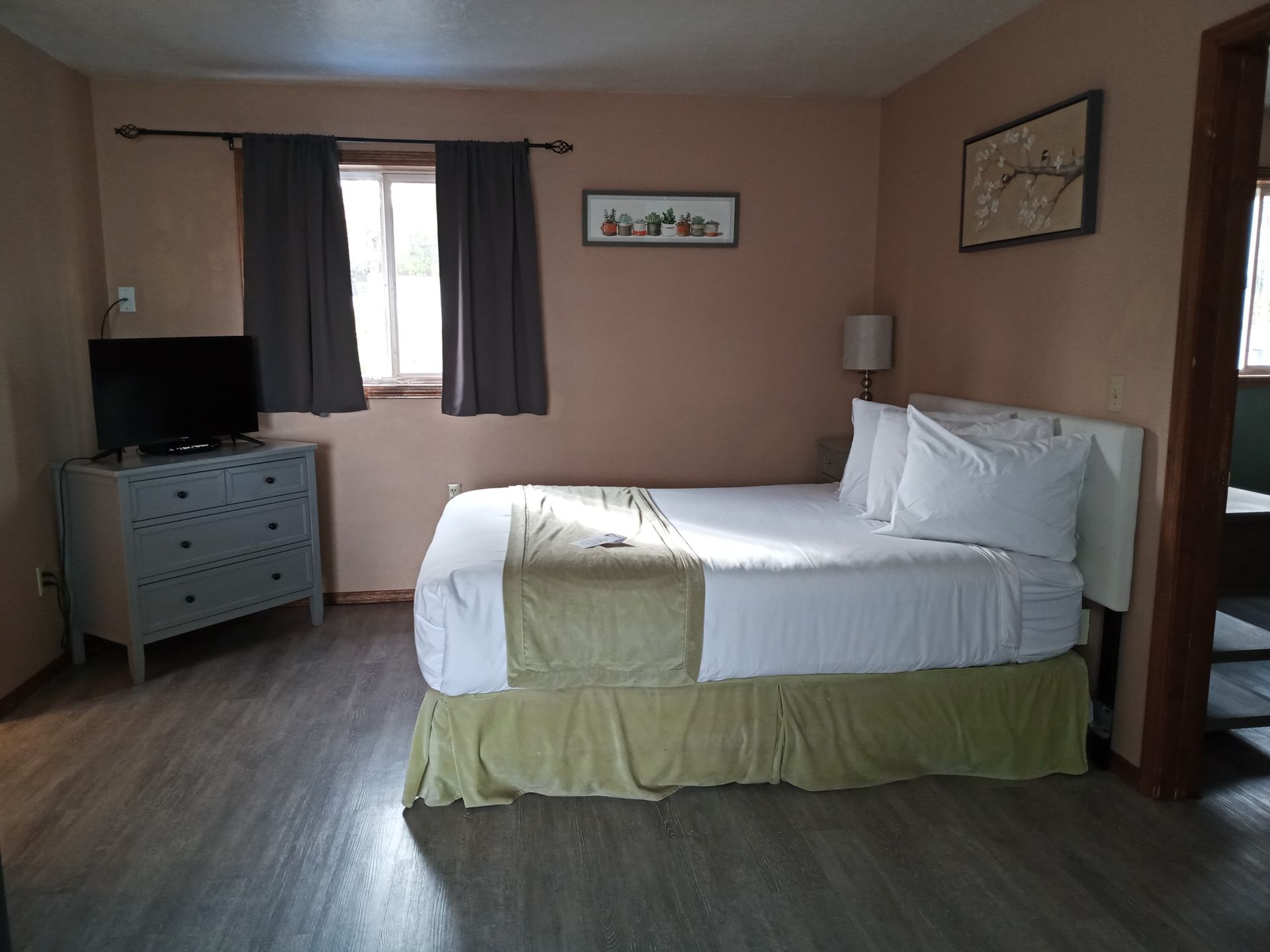 A hotel room with a bed , dresser and television.