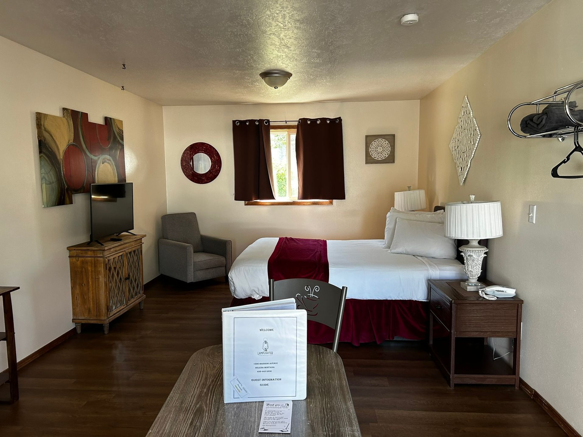 A hotel room with a bed , chair , table and television.