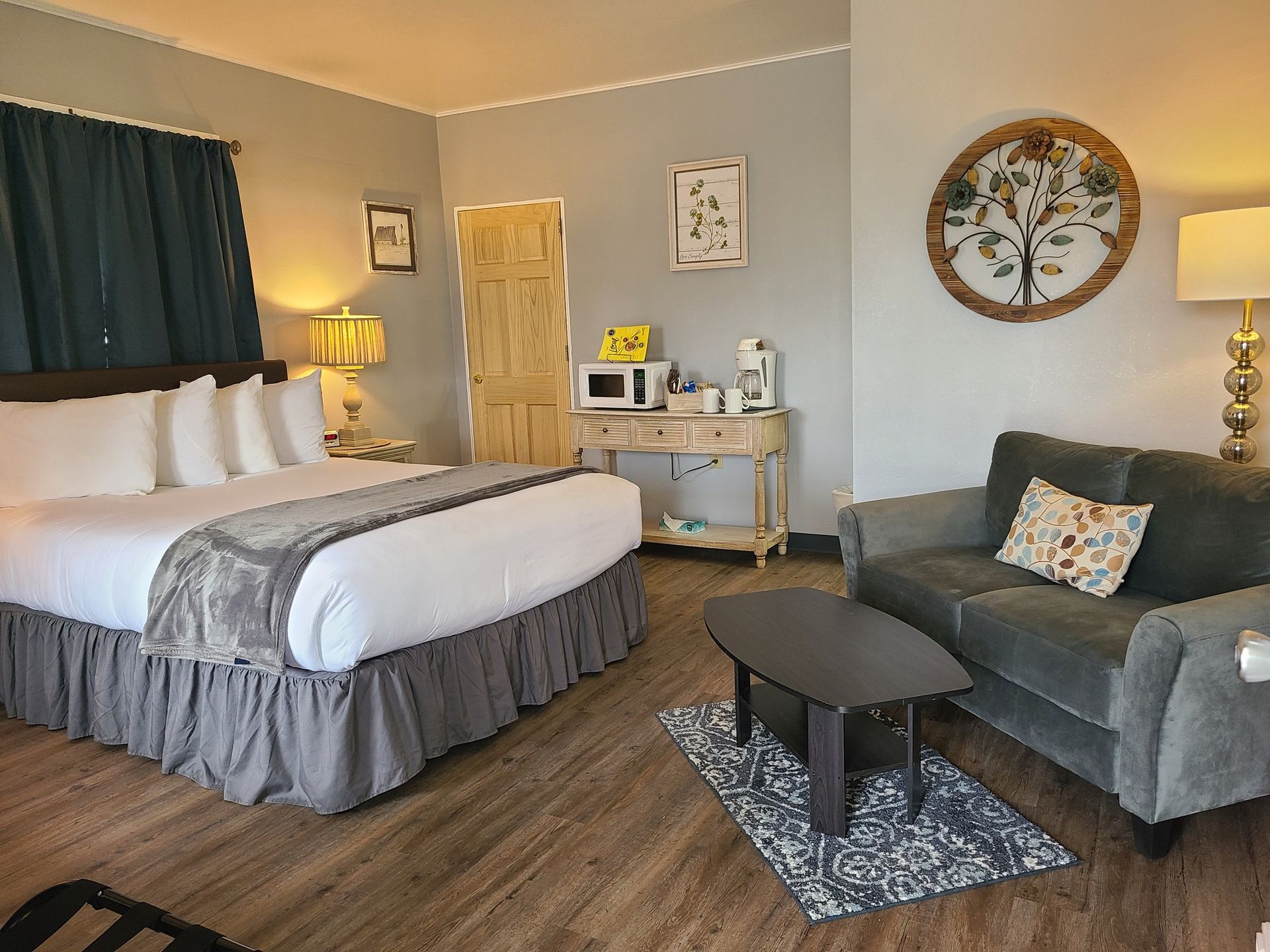 A hotel room with a king size bed , a couch , and a coffee table.