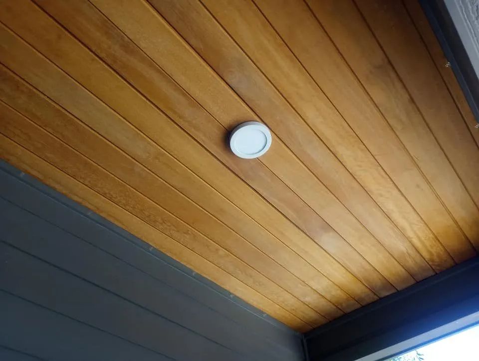 A circular, recessed light fixture centered on a ceiling paneled with warm-toned, horizontal wooden planks.