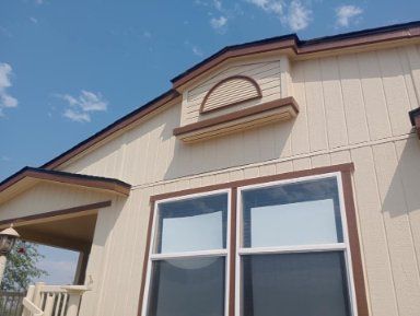 The exterior of a beige house with vertical siding, a window, and a decorative arched vent on the roof gable.