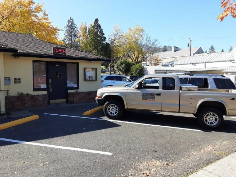 A tan pickup truck parked in front of a small building with an 