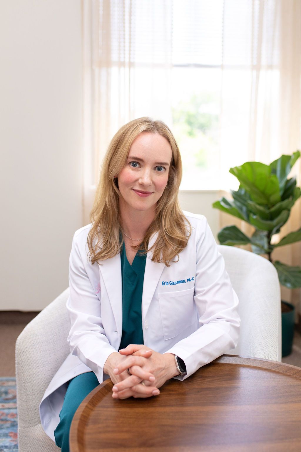 Medical professional in white coat holding a clipboard and vial, smiling in a bright clinic