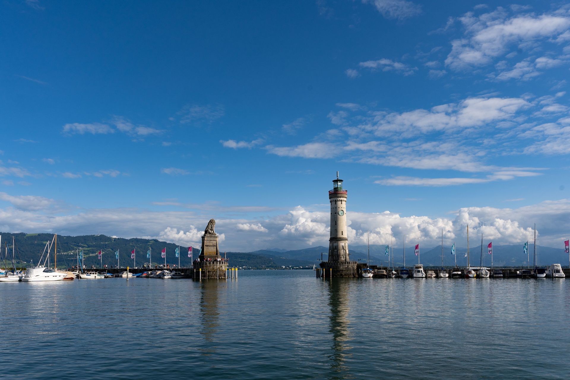 Hafeneinfahrt von Lindau am Bodensee mit dem weißen Leuchtturm und dem bayerischen Löwen, dahinter d
