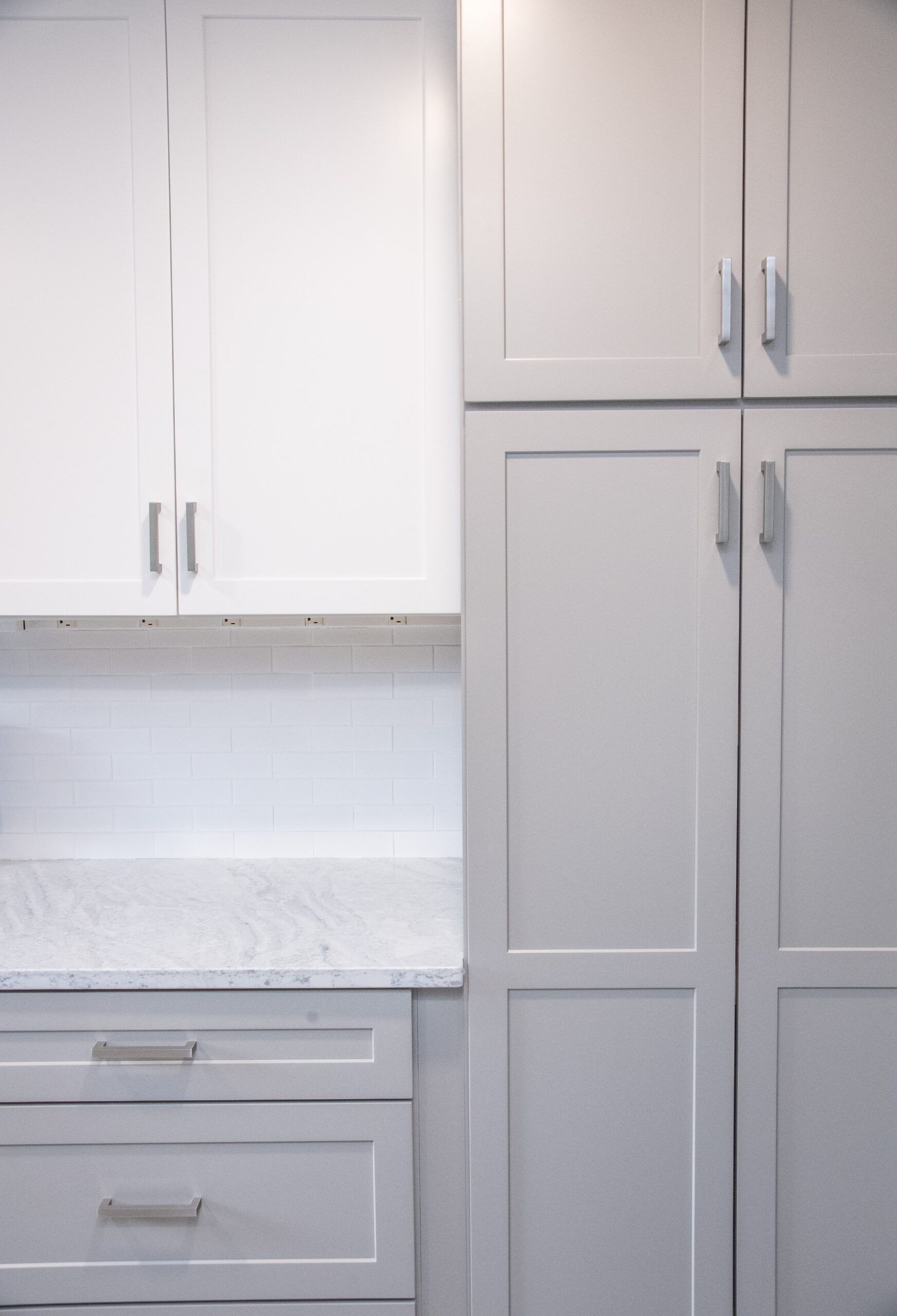 White kitchen cabinets and drawers with a light countertop and tiled backsplash.