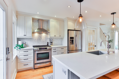 Bright modern kitchen with white cabinets, stainless steel appliances, and a large white island.