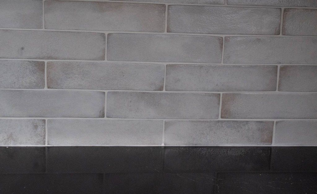 Gray cinder block wall with a dark black band along the bottom