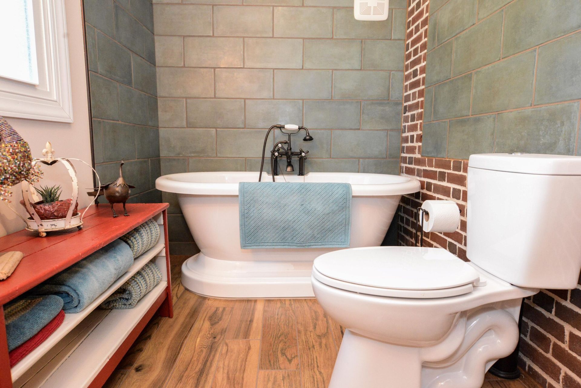 Small bathroom with clawfoot tub, white toilet, teal tile walls, and wood floor