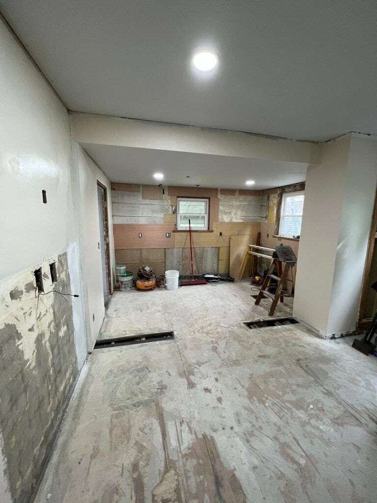 Renovated room with stripped floors, exposed walls, recessed lights, and a kitchen area at the back