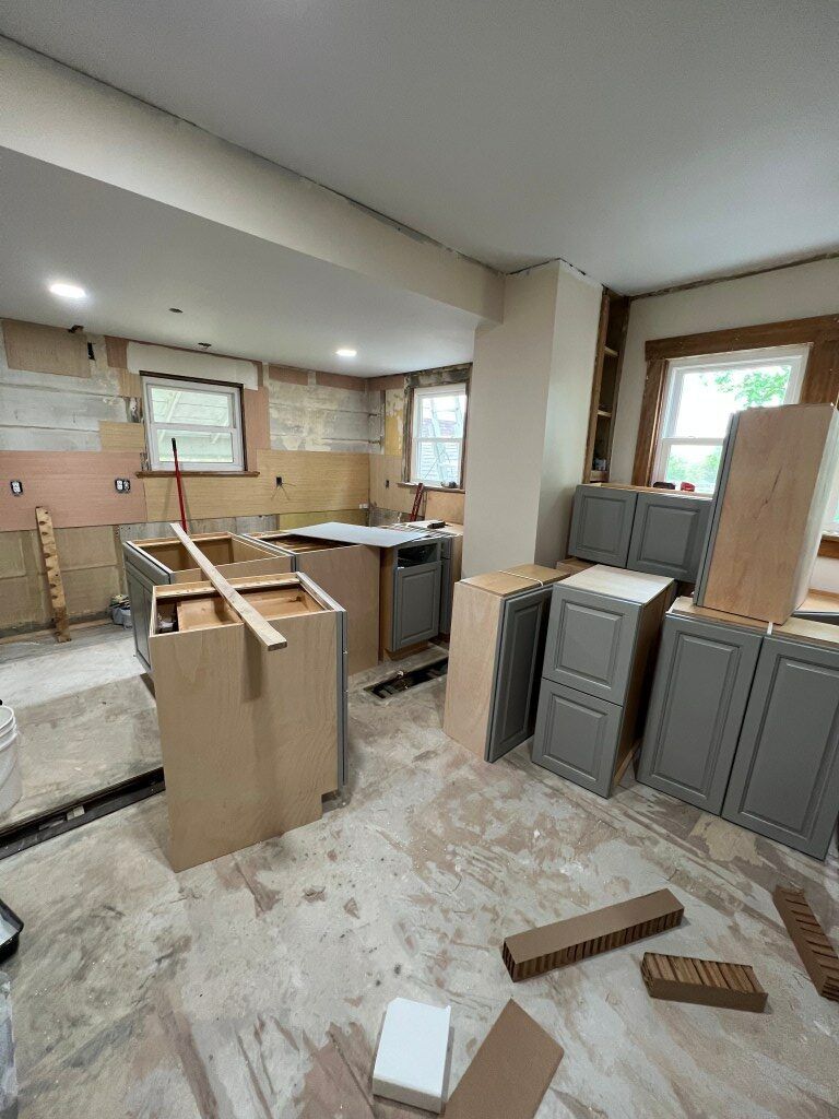 Renovated kitchen with unfinished cabinets, countertop, and scattered bricks on the floor
