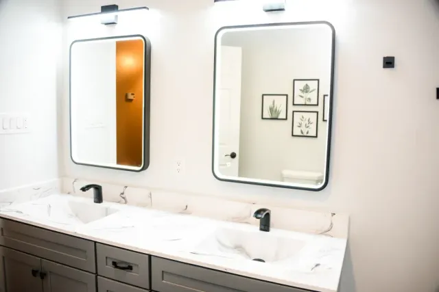 Modern bathroom with double sinks, large mirrors, and white marble countertops