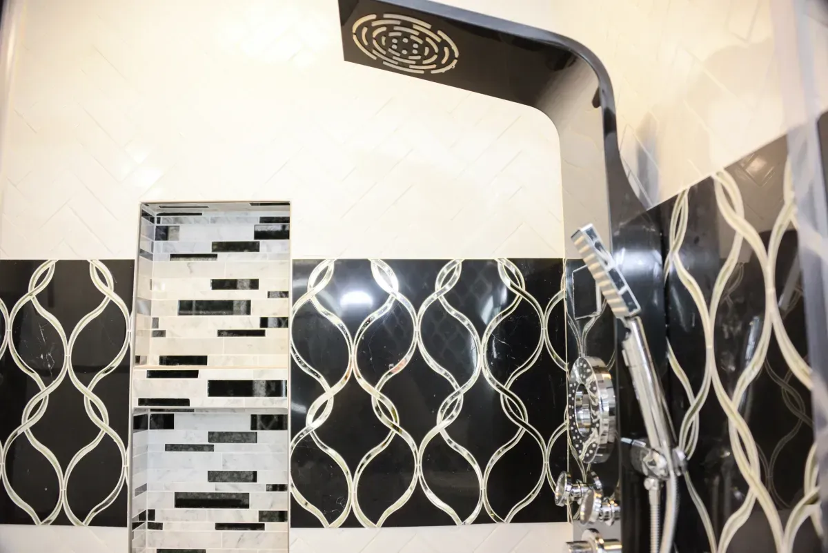 Modern shower with black-and-white patterned tiles and a chrome rain showerhead.