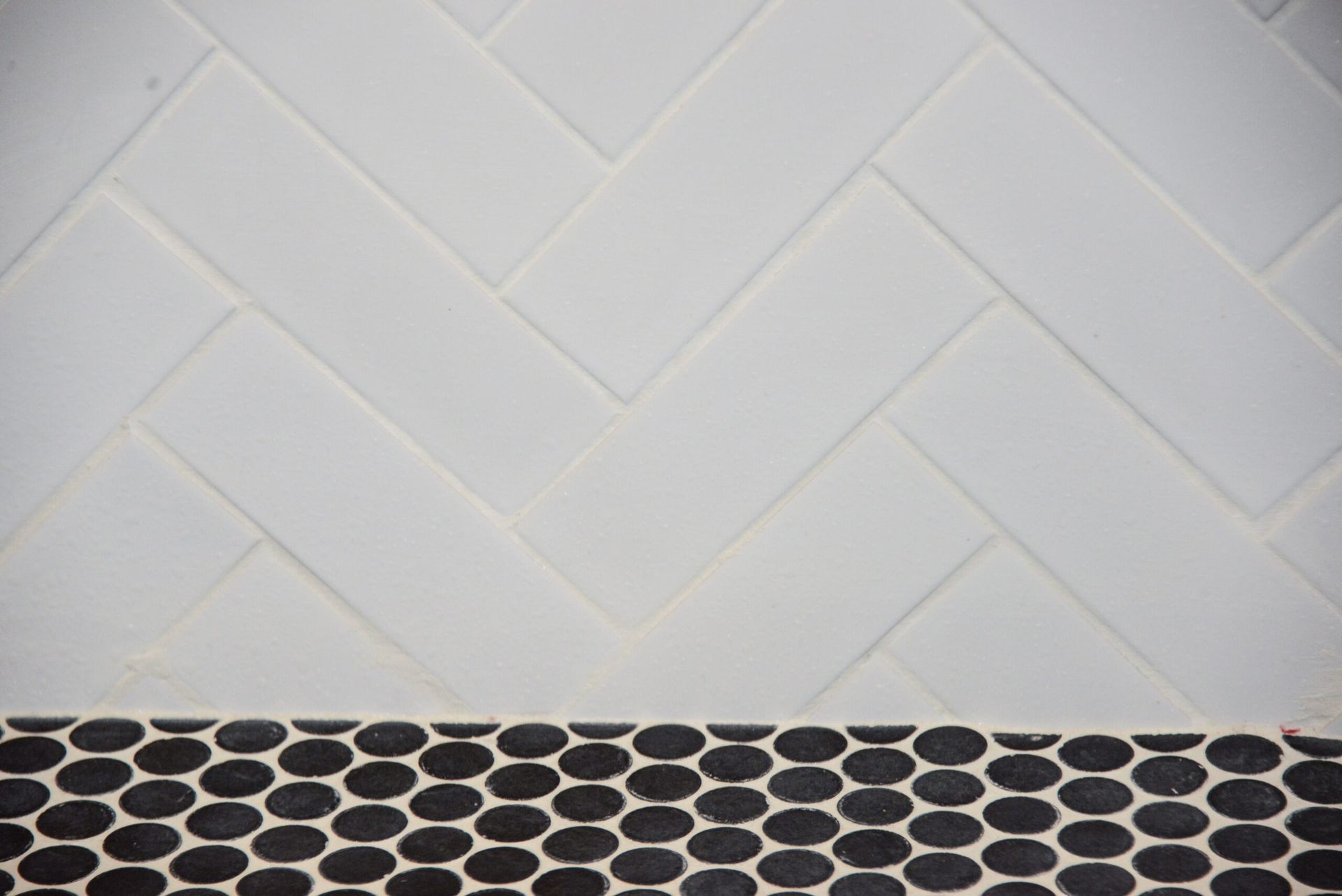 White herringbone tile wall above a black oval-patterned countertop or backsplash border