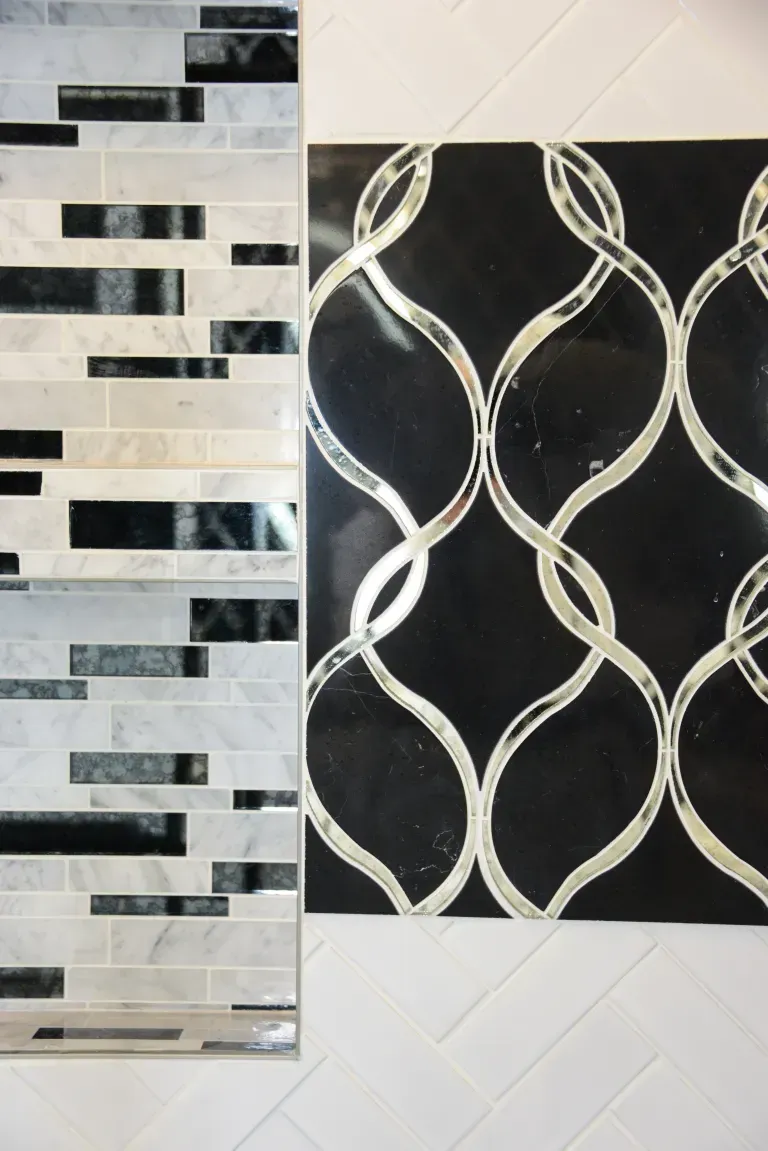 Two decorative wall tiles: black-and-white mosaic strips beside a black tile with white interlocking loops.