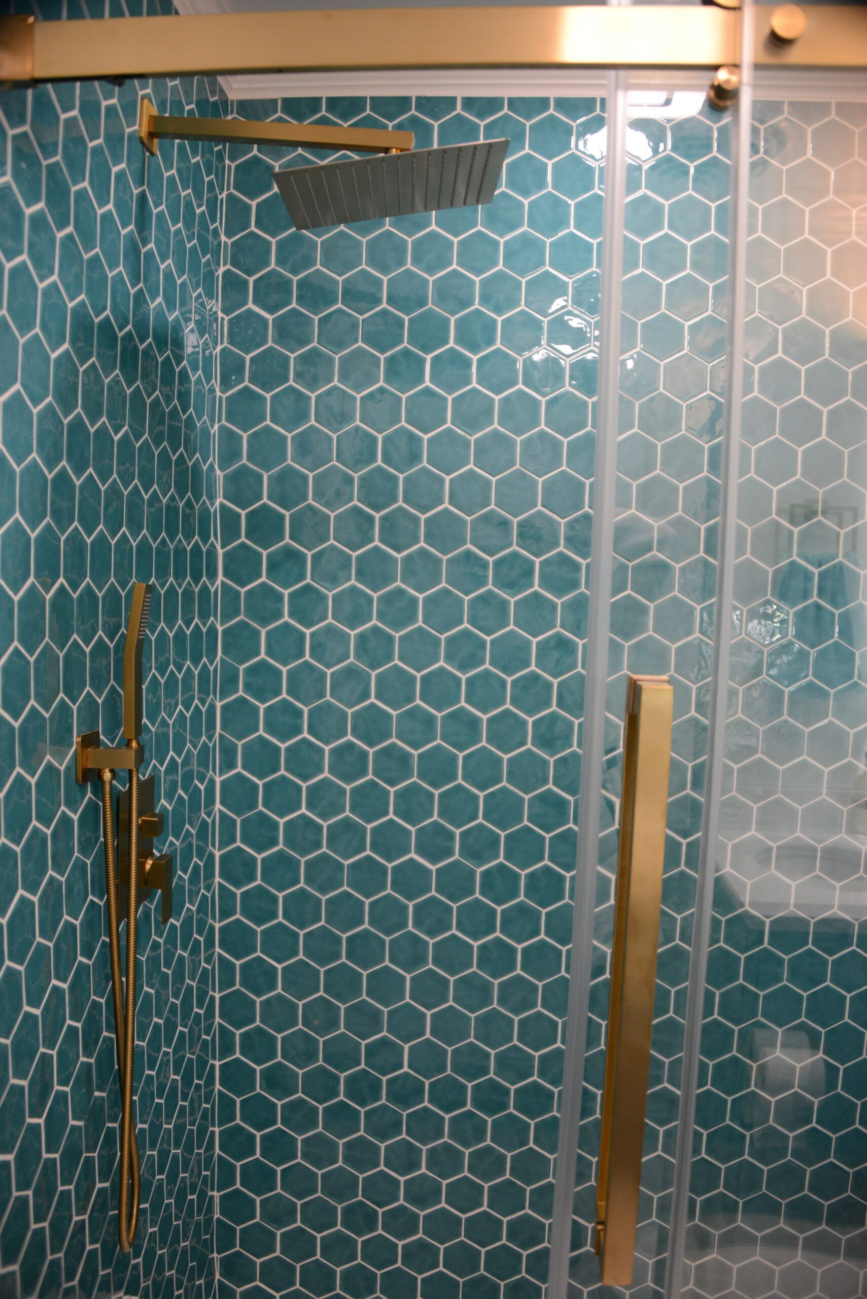 Blue hexagon-tile shower with glass door and brass fixtures