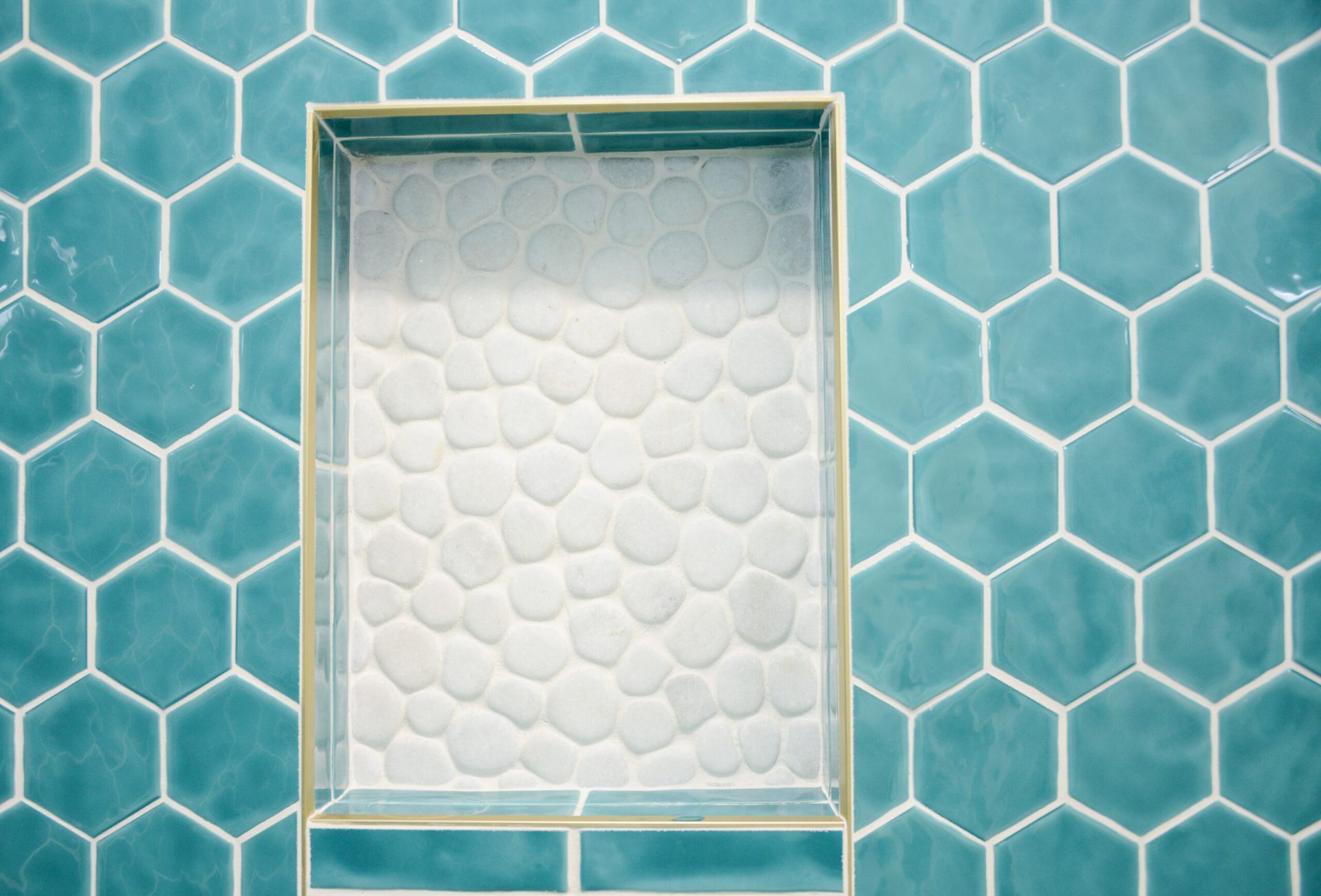 Turquoise hex tile wall with a recessed white textured panel in the center