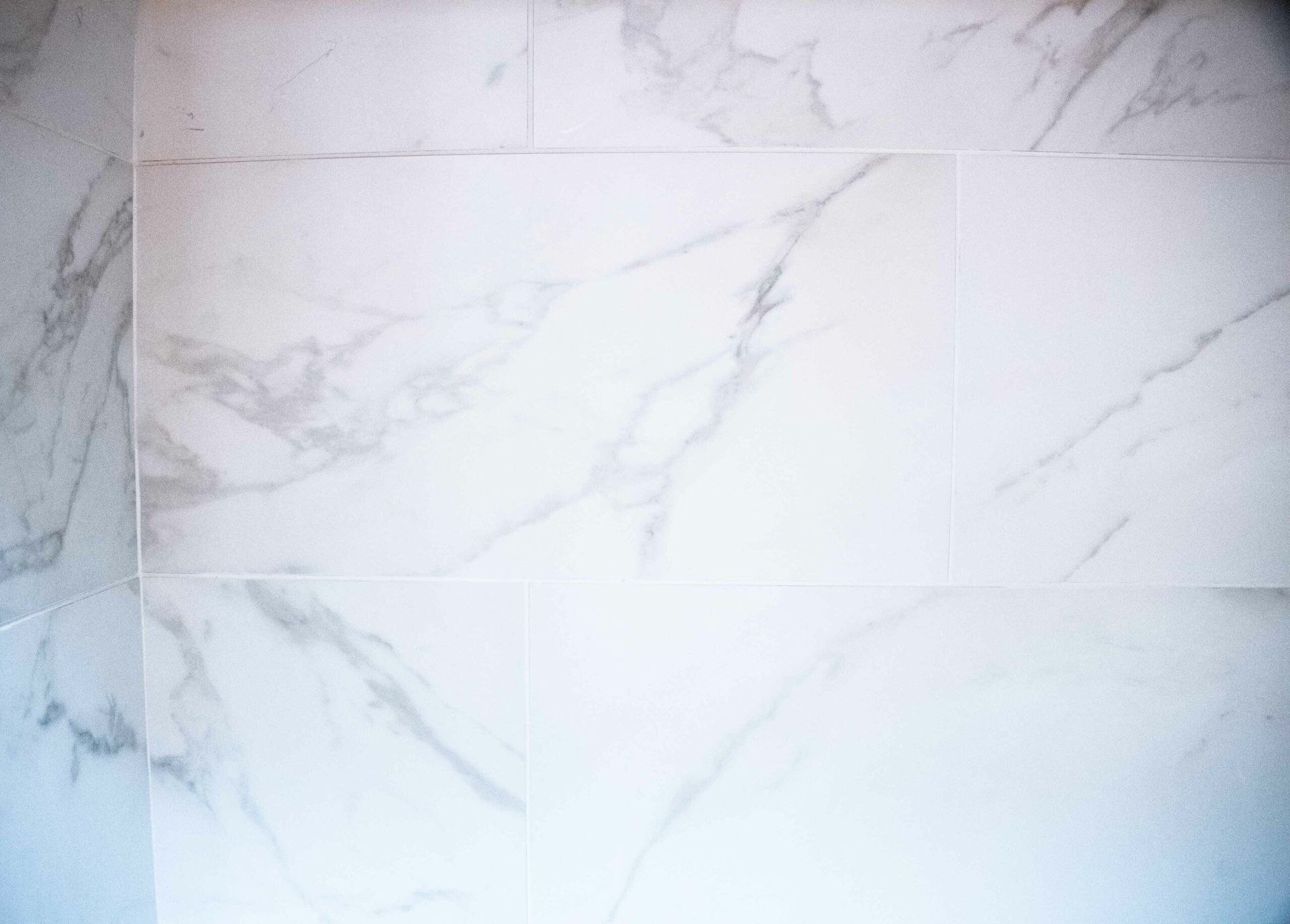 White marble tile wall with light gray veining and subtle panel seams