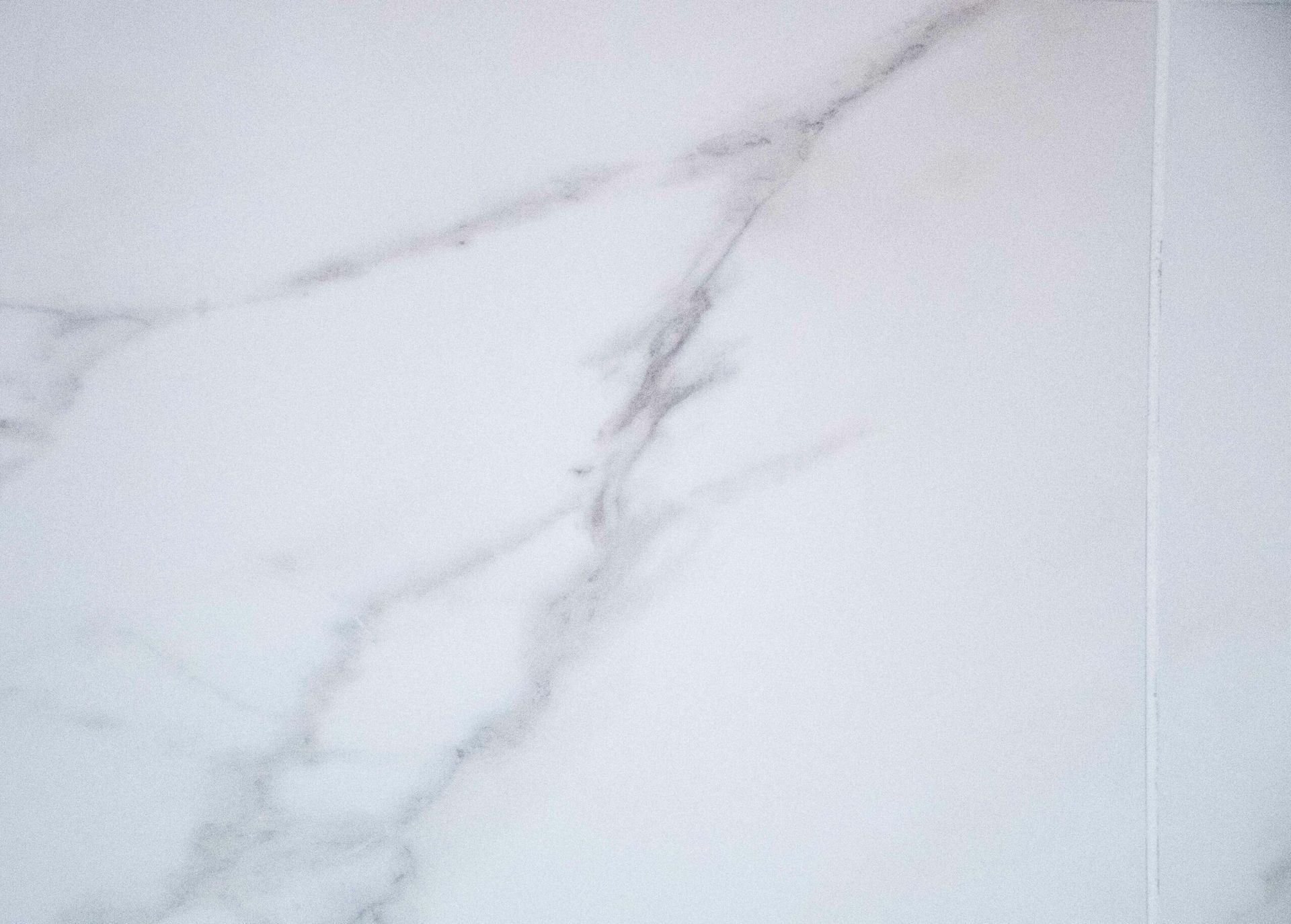 White marble surface with subtle gray veining and a vertical seam on the right