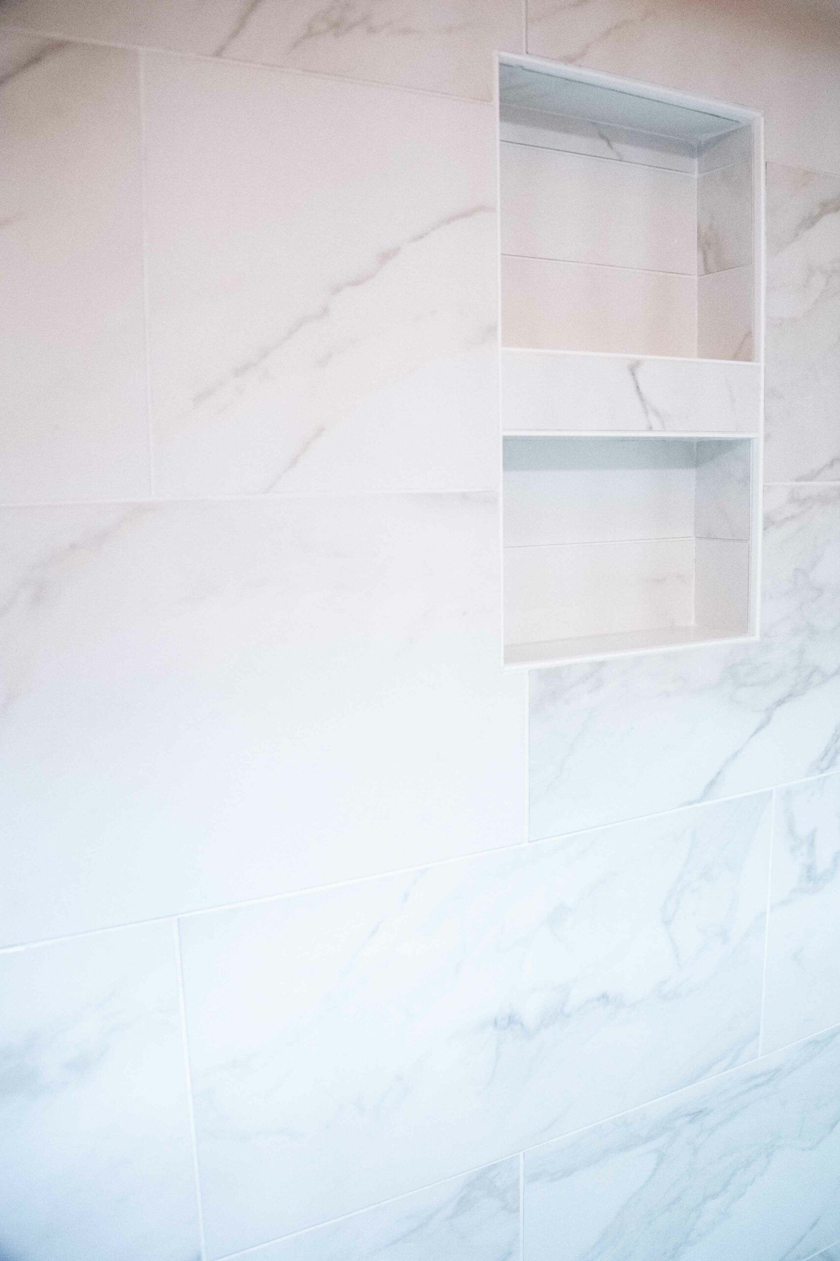 White marble-look tiled wall with a built-in rectangular niche shelf.