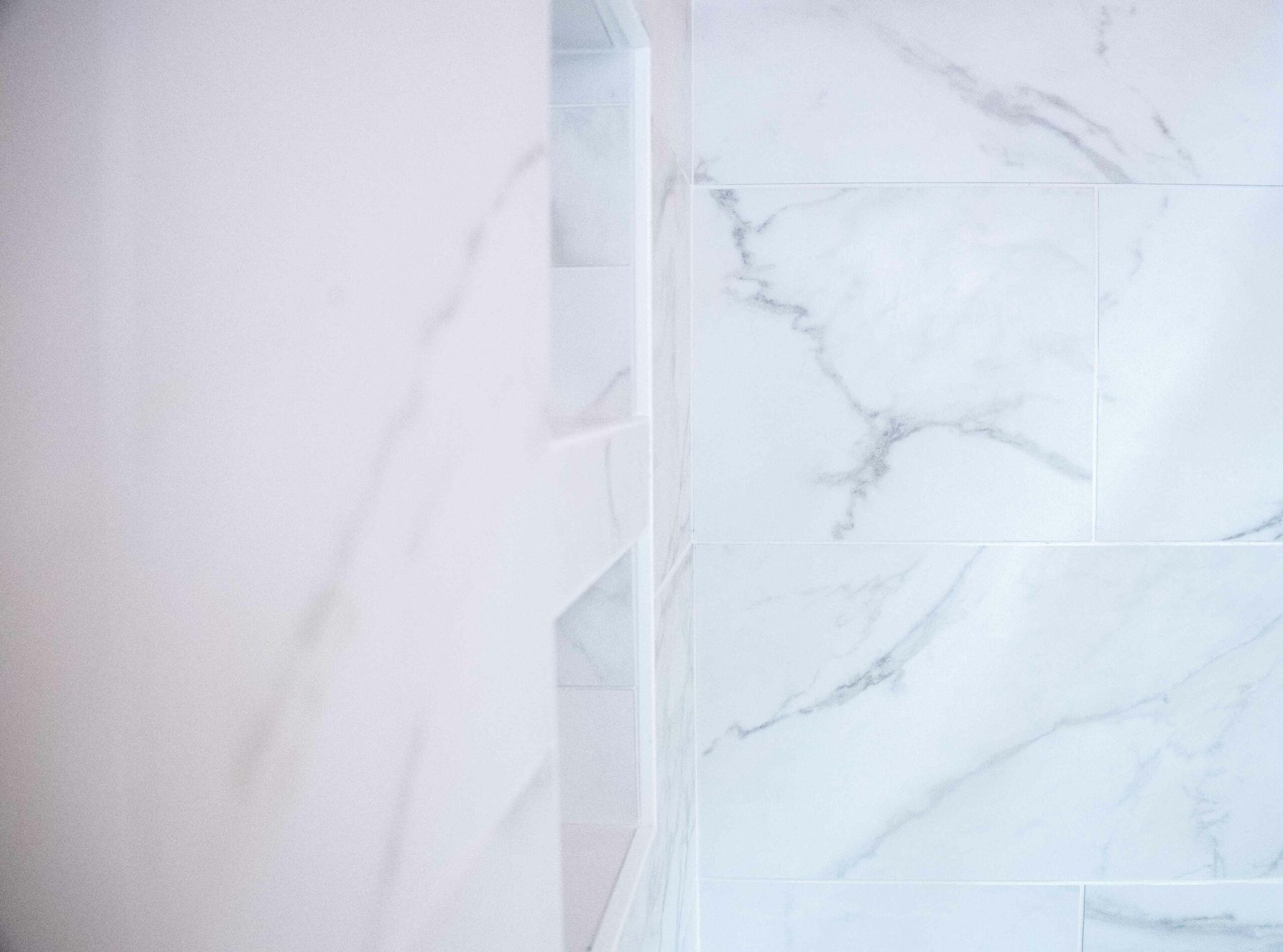 White marble tile wall with a narrow vertical accent strip and subtle gray veining