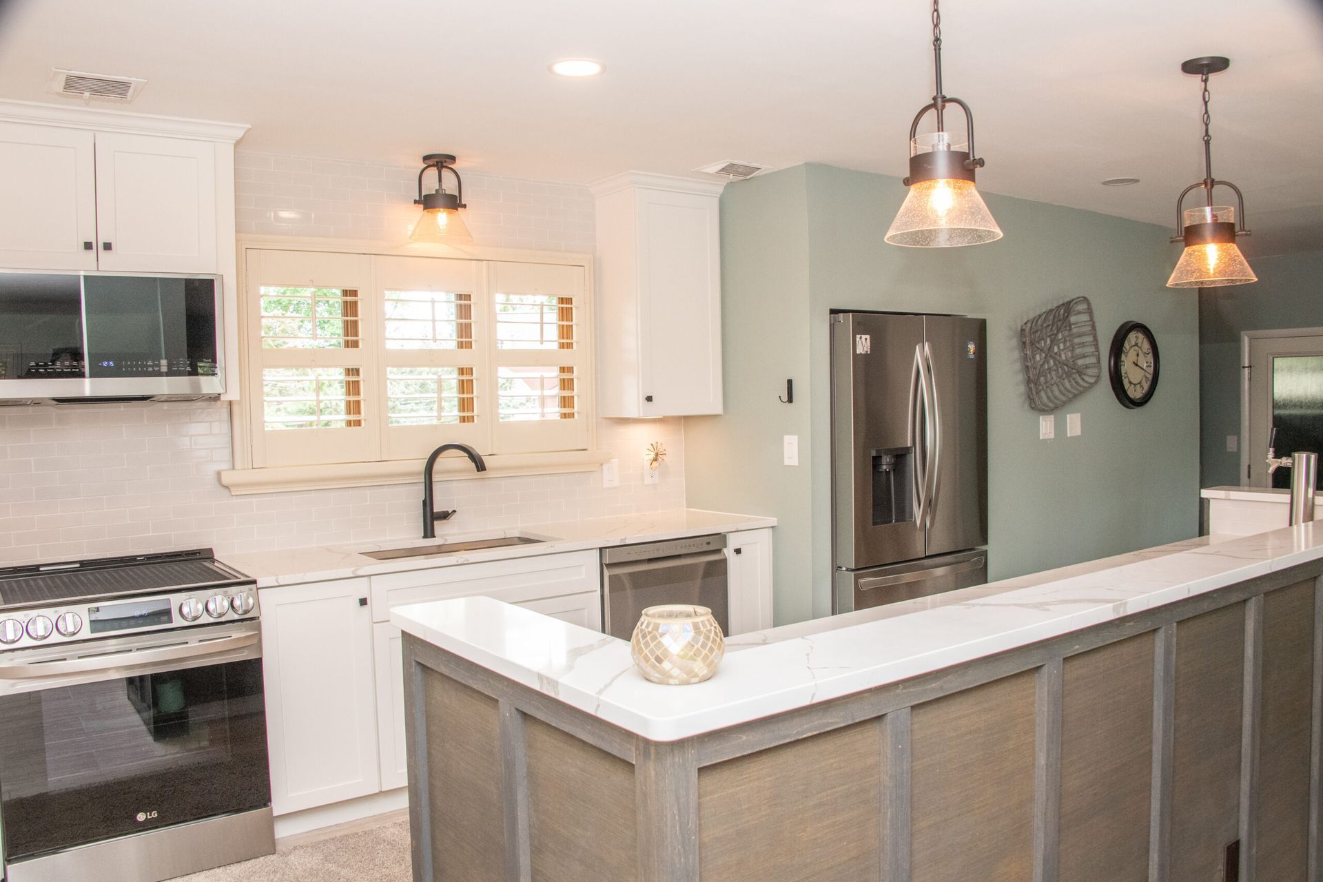 Bright modern kitchen with white cabinets, stainless appliances, island, and pendant lights
