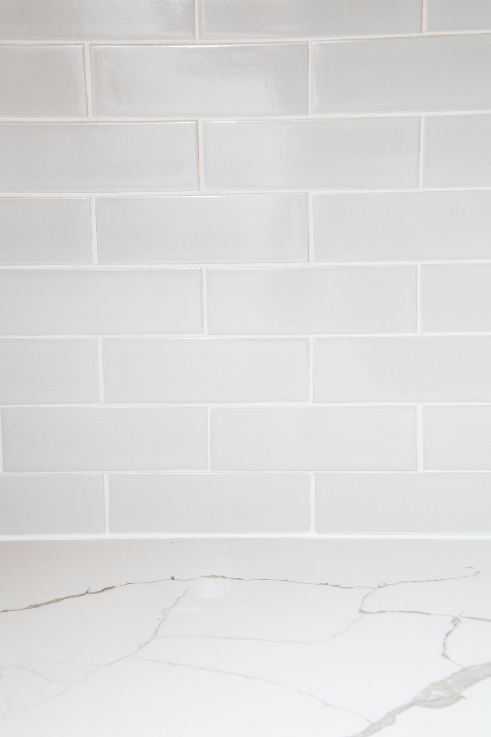 White subway-tile wall above a light marble countertop