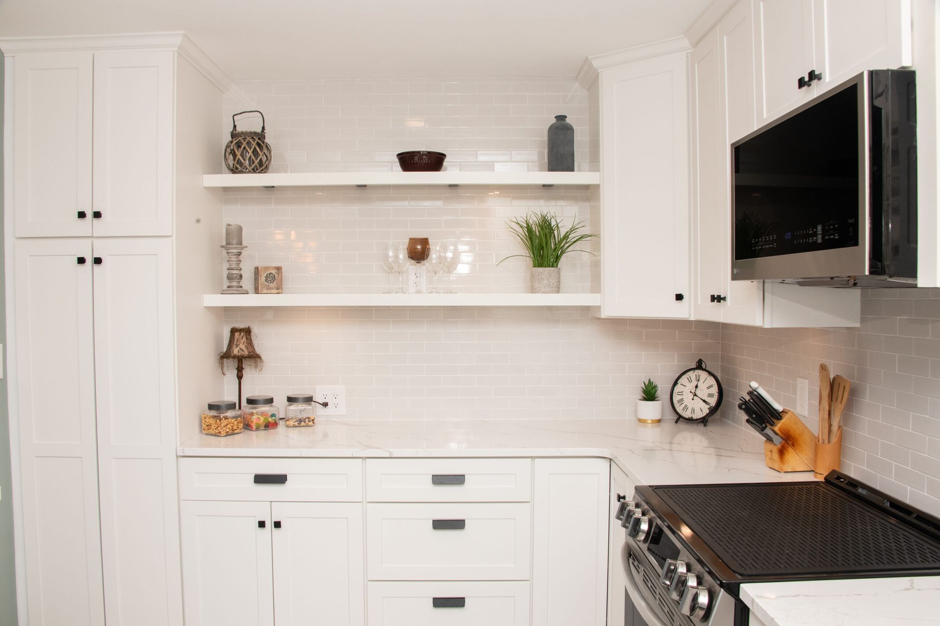 White kitchen with open shelves, built-in microwave, gas range, and countertop decor