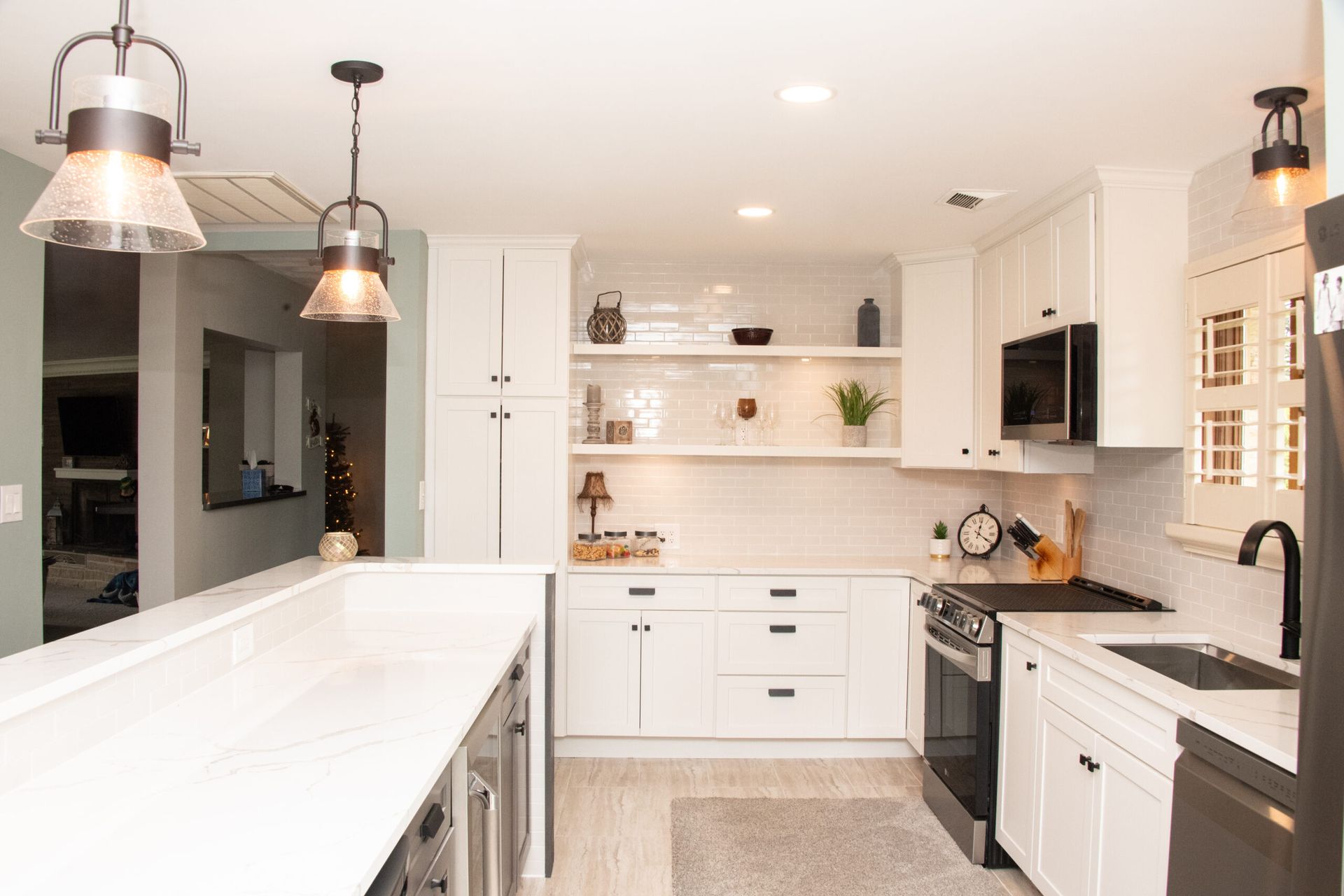 Bright modern white kitchen with island, pendant lights, open shelves, and stainless steel appliances