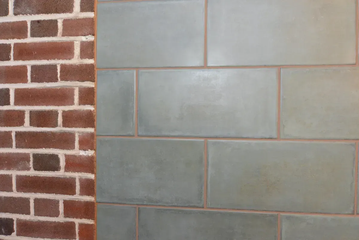 Brick wall beside light gray cinder block wall with vertical seam