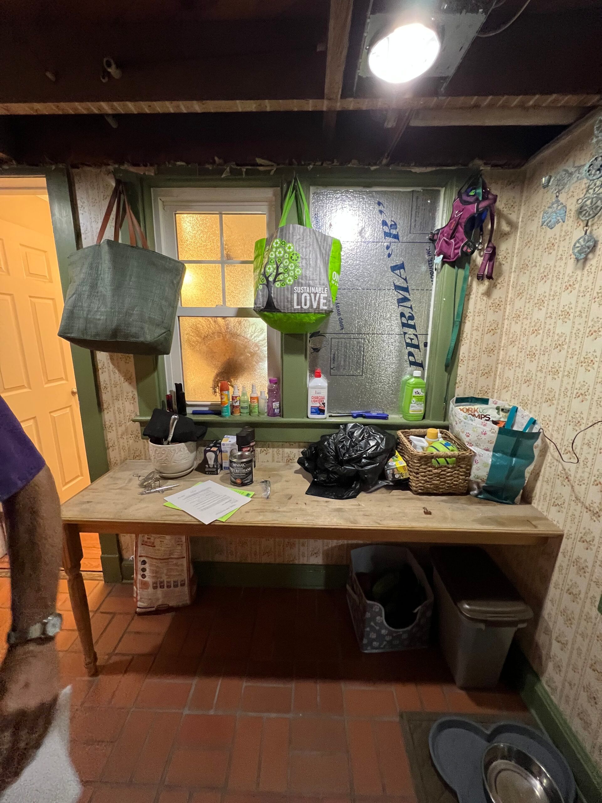 Small rustic kitchen with wooden counter, hanging plants, sink, stove, and tiled floor.