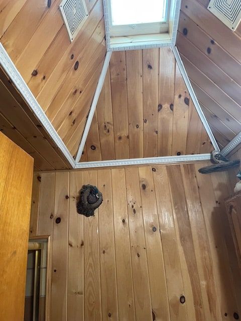 Wood-paneled cathedral ceiling with skylight and exposed beams; round wall opening near the center.