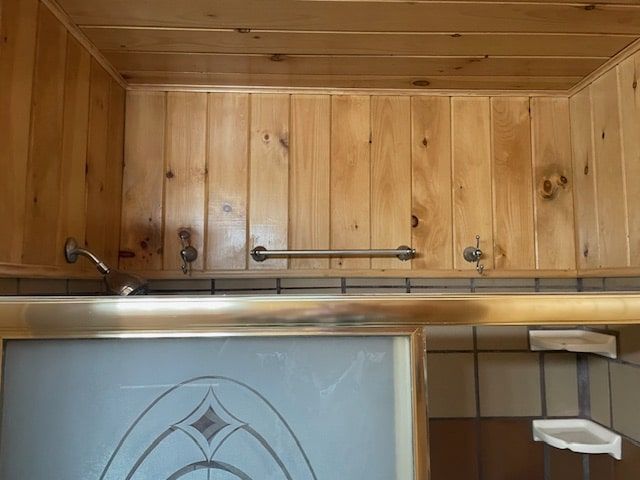 Wood-paneled kitchen wall with upper cabinets and a dishwasher door below