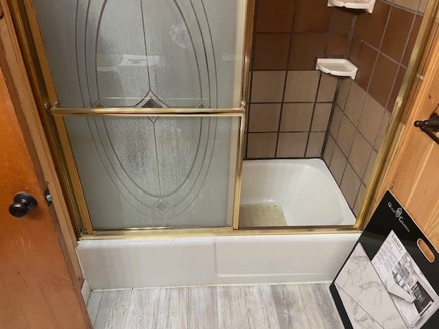 Small bathroom with a frosted sliding shower door, tub, and tan tile walls.