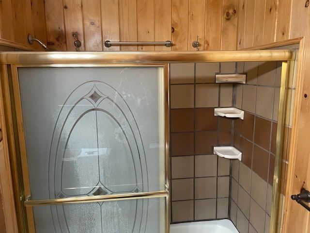 Glass shower enclosure with brass frame and tiled bathroom walls