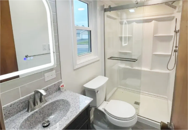 Accessible bathroom with walk-in shower, toilet, and granite sink vanity near a window