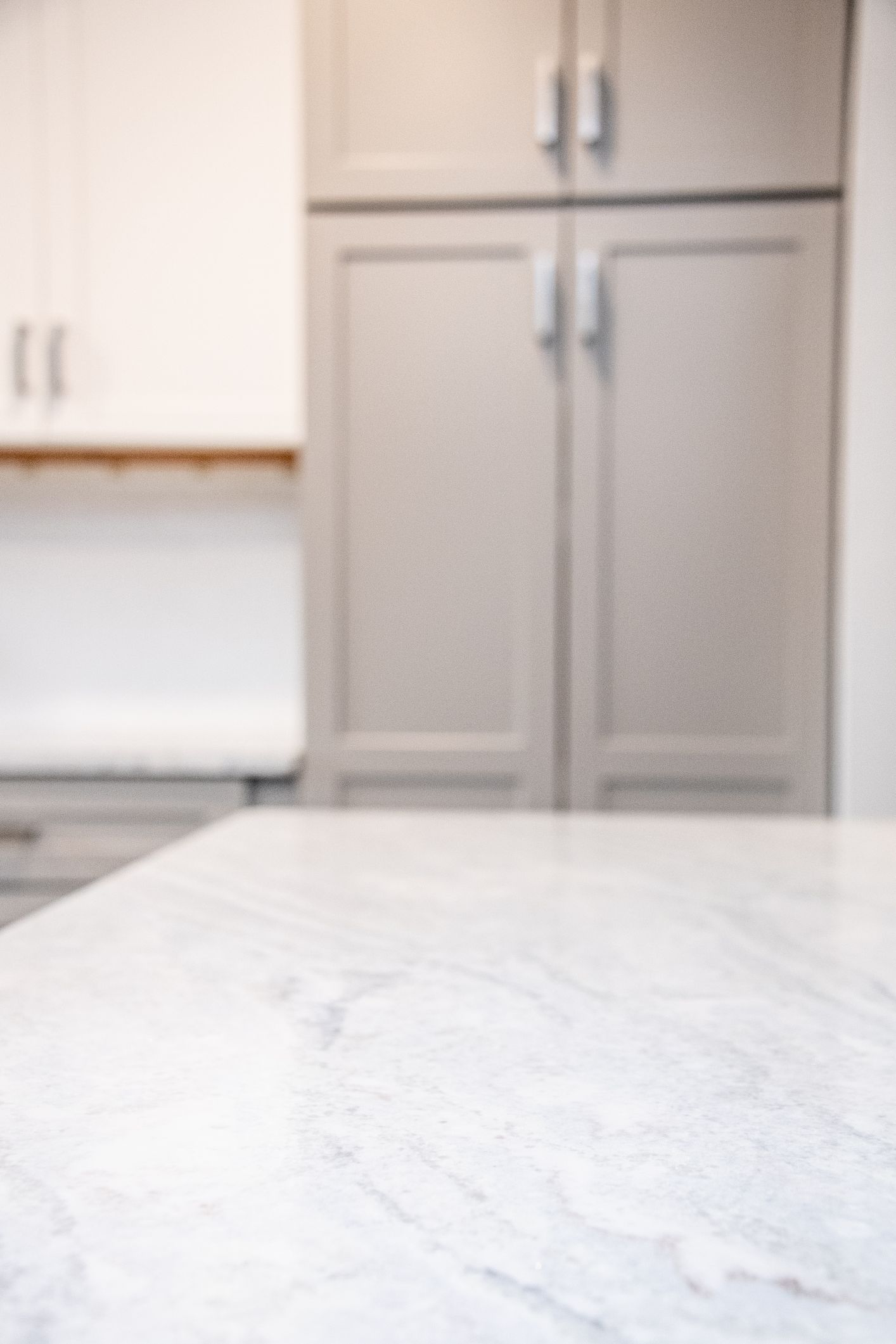 Empty kitchen with gray cabinets and a white marble countertop in the foreground
